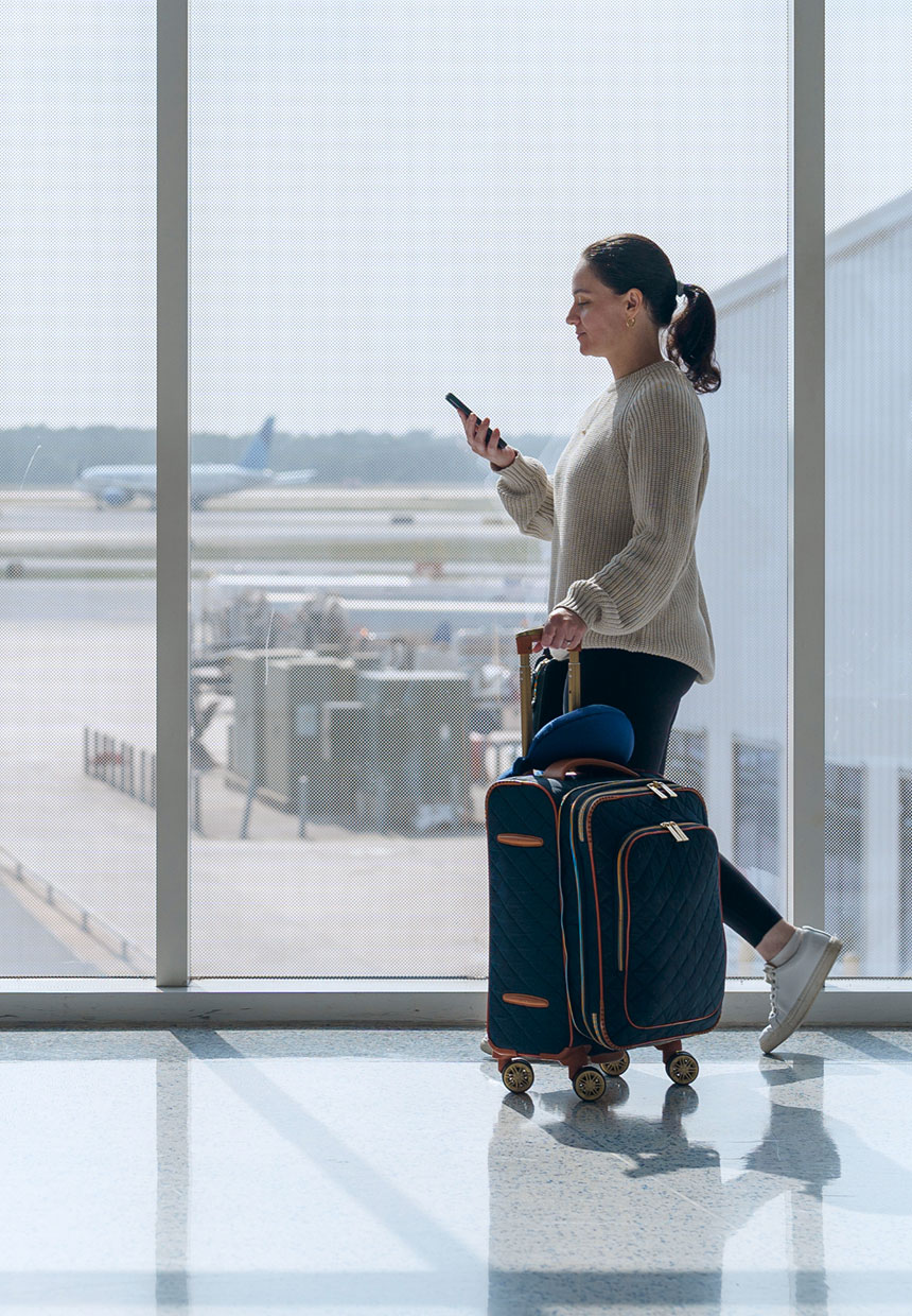 Reisende mit Koffer und Smartphone am Flughafen